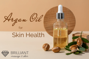 oil in a bottle dispenser with some argan fruits: text: argan oil for skin healthe