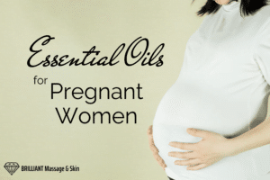 pregnant woman in white shirt while holding her tummy: text: essesntial oils for pregnant women